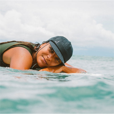 woman with a surf hat laying on a surfboard